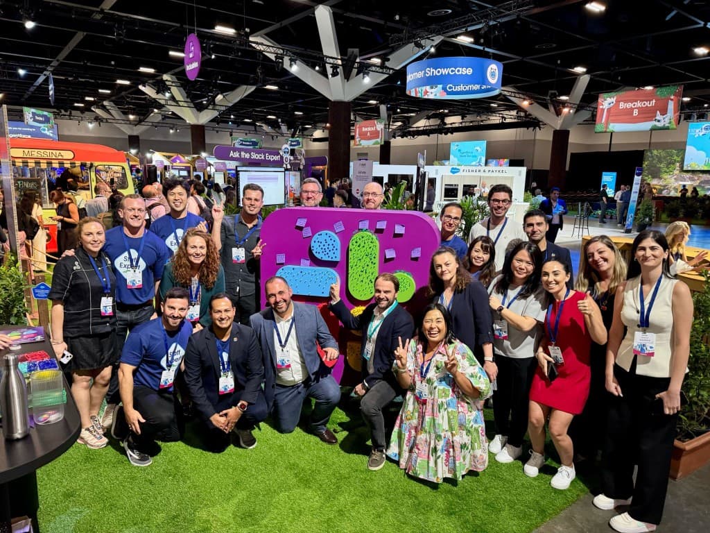 Group at a trade show with Slack sculpture and Staff Expert shirts, Customer Showcase signage