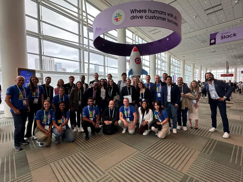 Slack Global Solutions Engineering team at Dreamforce 2024 under a banner reading where humans with AI drive customer success